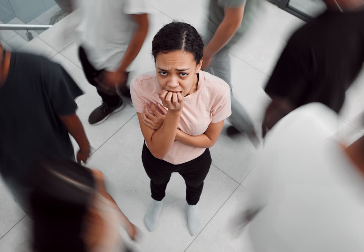 Shot of a young woman experiencing mental illness while being surrounded by people inside.